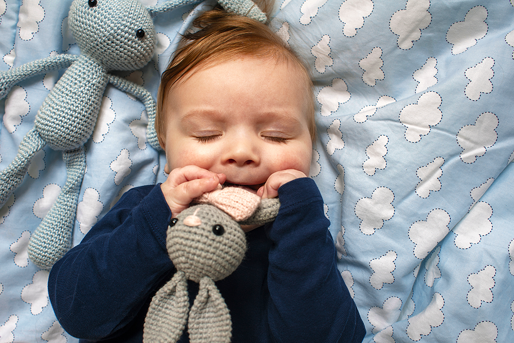 Baby sleeping in crib with teething rattle