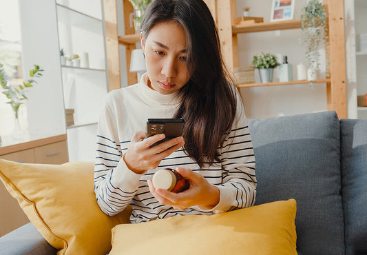 Mom lookin at vitamin bottle with phone