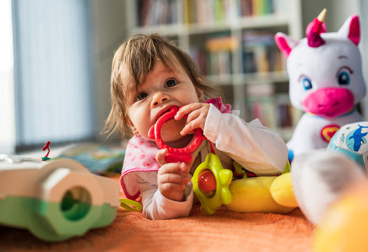 Colorful baby with teething ring and stuffed unicorn